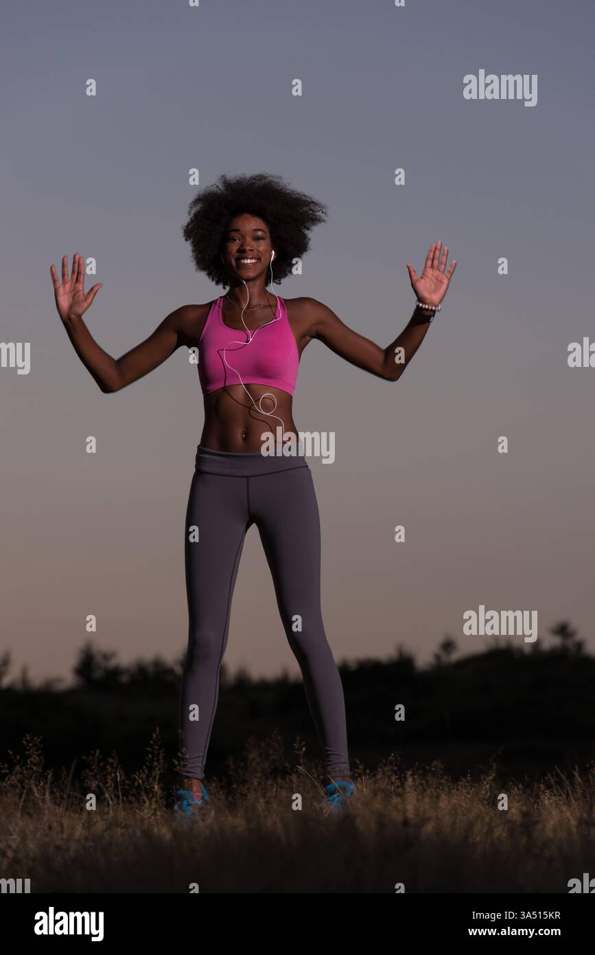 Jeune femme en bonne santé effectuant des exercices d'étirement comme échauffement après un jogging dans un cadre naturel lors d'une belle soirée d'été. Cette image de style de vie de fitness est idéale pour le bien-être, l'activité de plein air et les campagnes de vie active. Banque D'Images