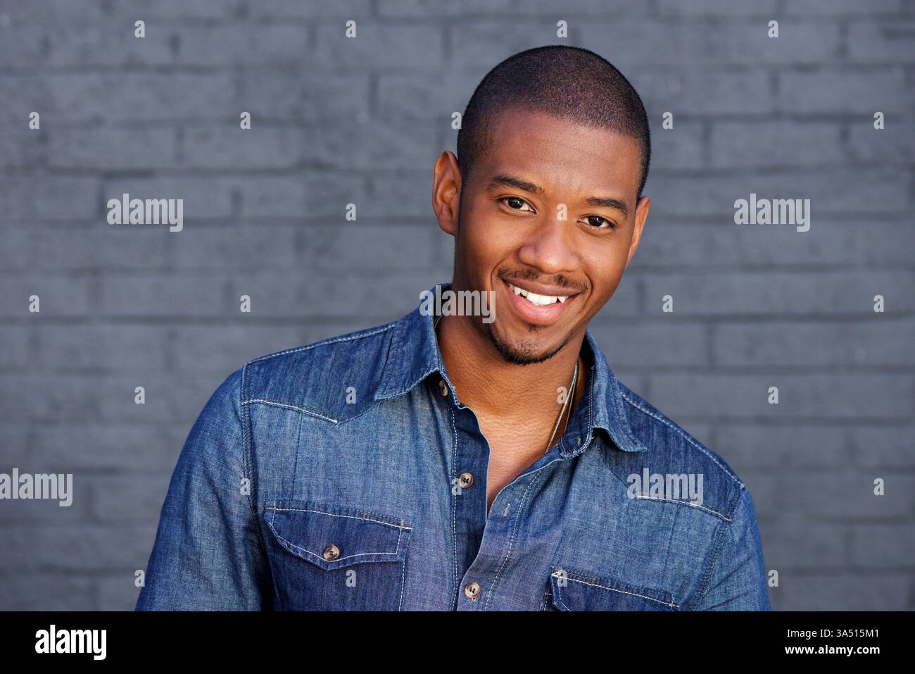 Portrait d'un homme noir cool souriant dans une chemise bleue. Un style de vie contemporain qui transmet confiance, accessibilité et sens de la mode. Convient pour la marque personnelle, le style de vie et divers thèmes de représentation. Banque D'Images