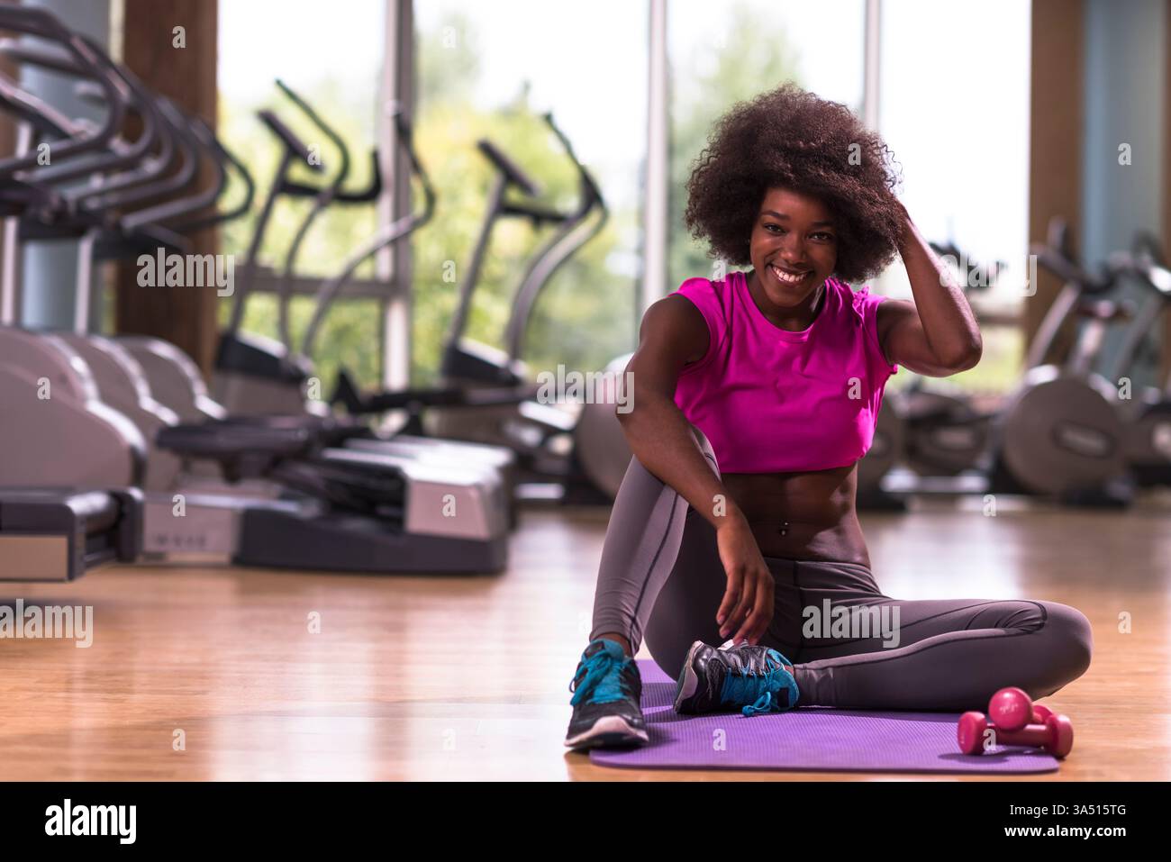 Belle jeune femme afro-américaine pratiquant le yoga dans un gymnase. Cette image de style de vie physique met en valeur l'équilibre, la flexibilité et la concentration pendant un entraînement. Banque D'Images