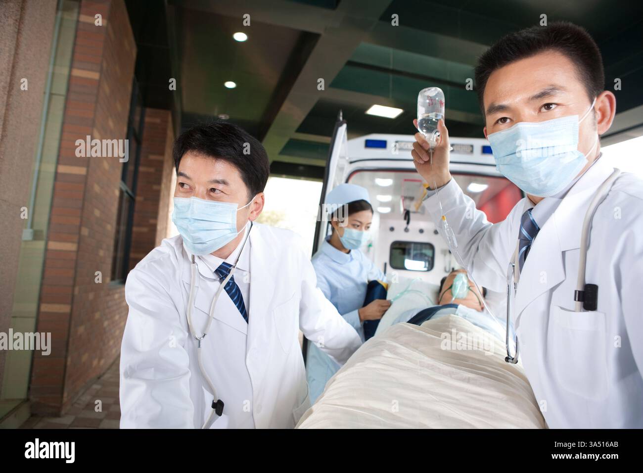 Travailleurs de la santé chinois déplaçant un patient d'une ambulance à l'hôpital. Cette image exprime l'urgence, les services médicaux d'urgence et le travail d'équipe dans les soins de première ligne. Banque D'Images
