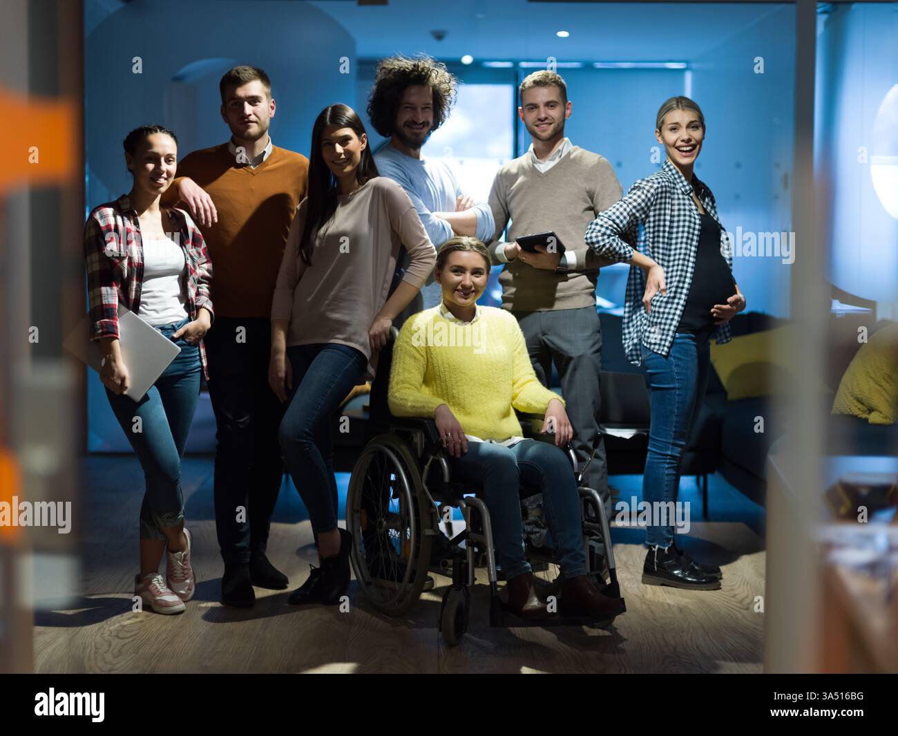 Femme d'affaires handicapée dans un fauteuil roulant travaille avec des collègues dans un bureau moderne ouvert. Illustre la diversité, l'inclusion et le travail d'équipe sur le lieu de travail. Banque D'Images