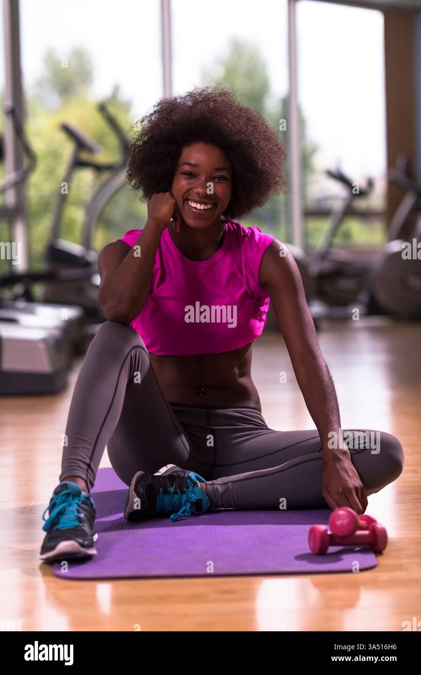 Belle jeune femme afro-américaine exerçant le yoga dans un gymnase. Cette image de fitness convient aux campagnes de bien-être, d'entraînement et de style de vie actif. Banque D'Images