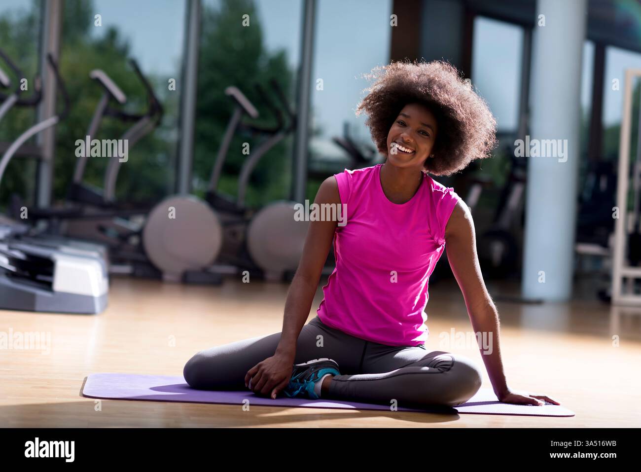 Belle jeune femme afro-américaine pratiquant le yoga dans un cadre de gym. Ce portrait de fitness ciblé capture l'équilibre et la force, idéal pour le bien-être, la marque de gym et les campagnes de vie saine. Banque D'Images