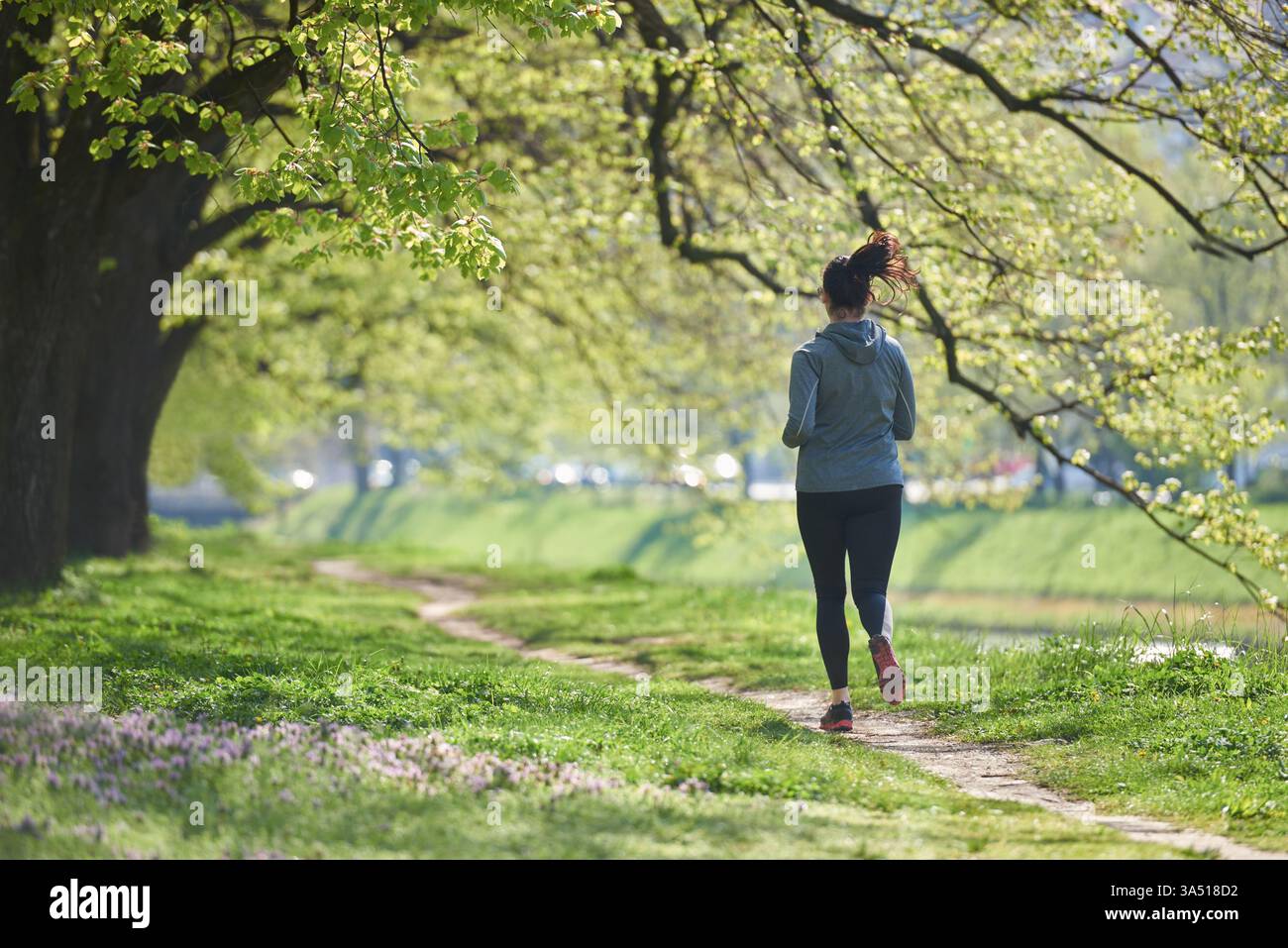 Mode de vie actif photo d'une femme faisant du jogging dans un parc portant des écouteurs pendant la journée. Idéal pour le fitness, les campagnes de bien-être et les loisirs en plein air. Énergique et sain, idéal pour le sport et le style de vie de marque. Banque D'Images