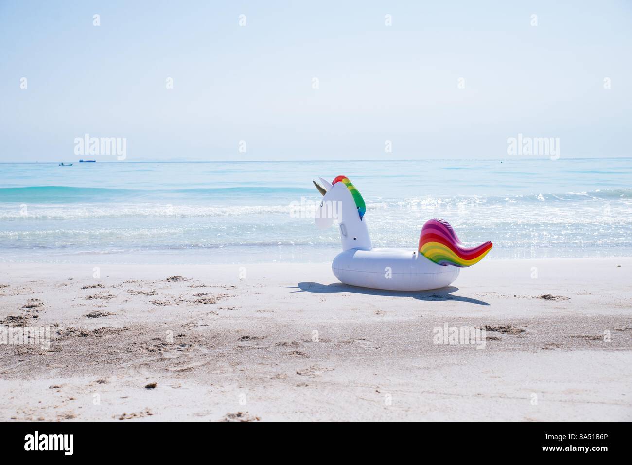 Flotteur gonflable licorne sur une plage ensoleillée crée une scène d'été ludique. Parfait pour les voyages, les vacances et les images de style de vie en bord de mer, avec un espace de copie clair de la plage et de la mer. Banque D'Images