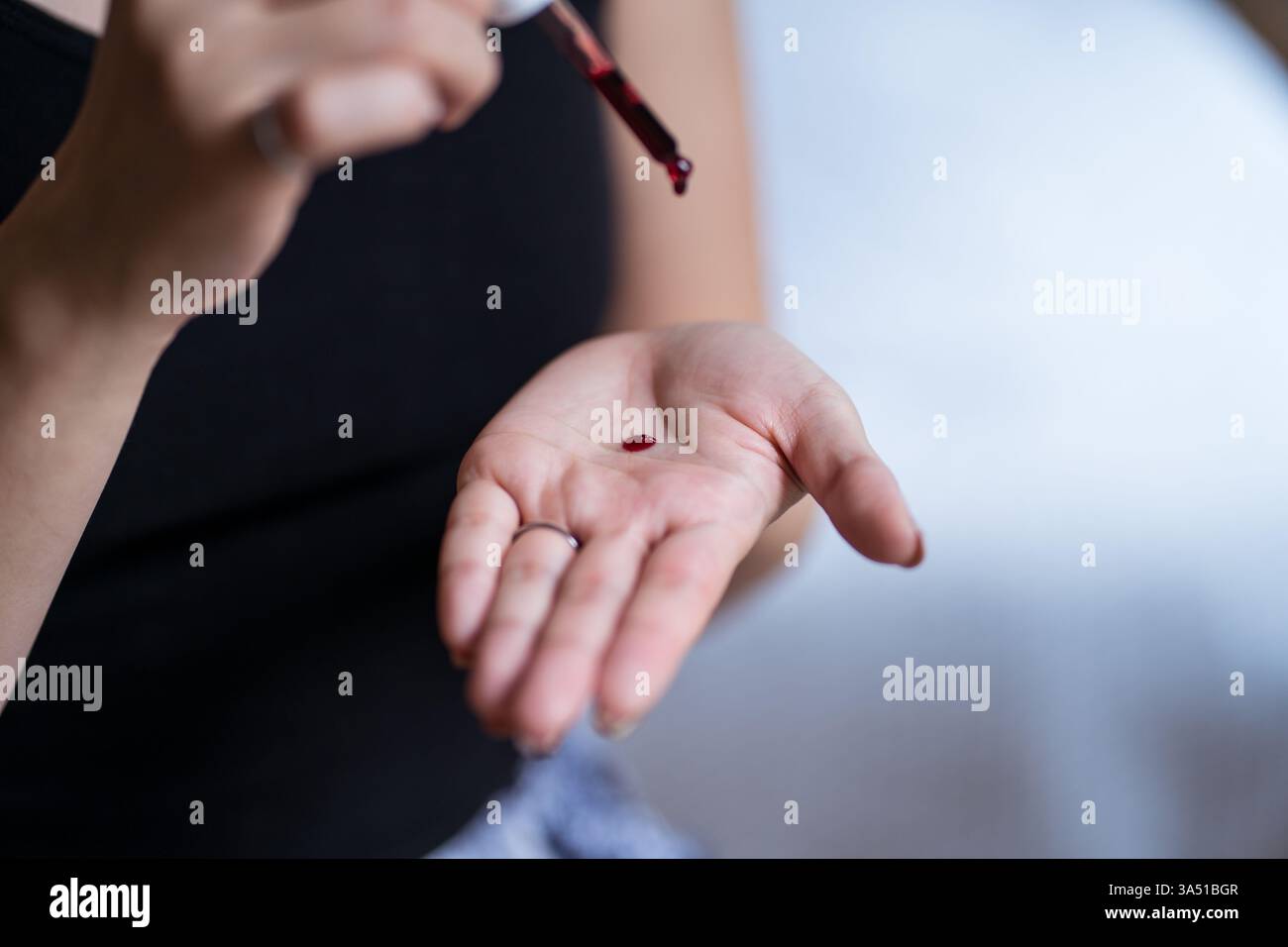 Femme asiatique utilisant une pipette pour vérifier la qualité des cosmétiques à la maison. La scène suggère des tests de beauté et une activité de laboratoire à domicile avec une ambiance professionnelle. Idéal pour les cosmétiques, le contrôle qualité et l'imagerie Home Science. Banque D'Images