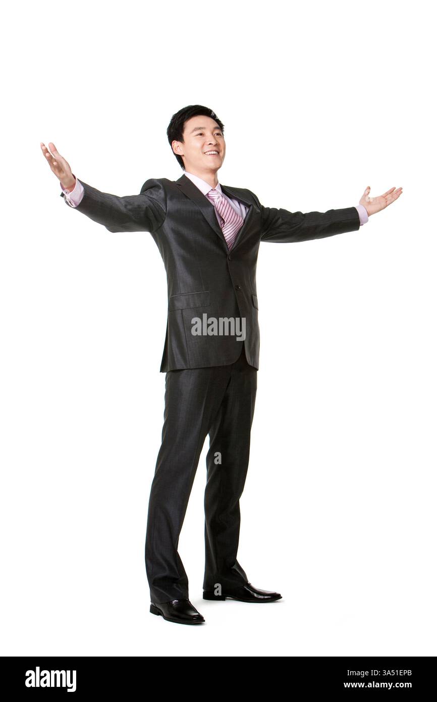 Portrait en pied d'un homme d'affaires chinois avec les bras tendus dans un cadre de studio. Fait preuve de confiance et de leadership tourné vers l'avenir pour les thèmes de l'entreprise ou de la réussite. Banque D'Images