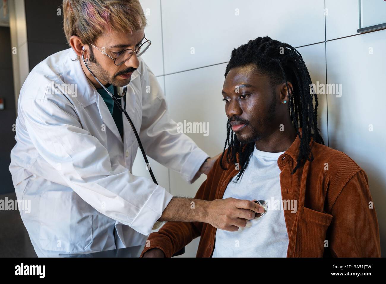 Un professionnel de la santé examine attentivement un patient masculin dans un cadre clinique moderne, évaluant les signes d'hypoglycémie. Cette scène d'examen médical met en évidence les soins professionnels, la surveillance de la glycémie et le diagnostic précis dans un établissement de santé. Vêtu d'un manteau clinique avec un stéthoscope, le clinicien transmet concentration et expertise. Banque D'Images