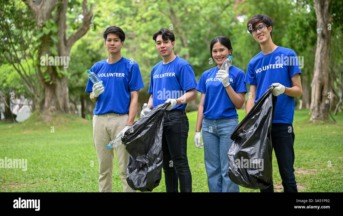 Groupe de jeunes volontaires asiatiques heureux en uniforme nettoyant un parc public avec des sacs en plastique. Idéal pour la RSE, le service communautaire et les campagnes environnementales mettant l'accent sur le travail d'équipe et l'énergie des jeunes. Soutient la communication autour du bénévolat et de l'impact social. Banque D'Images