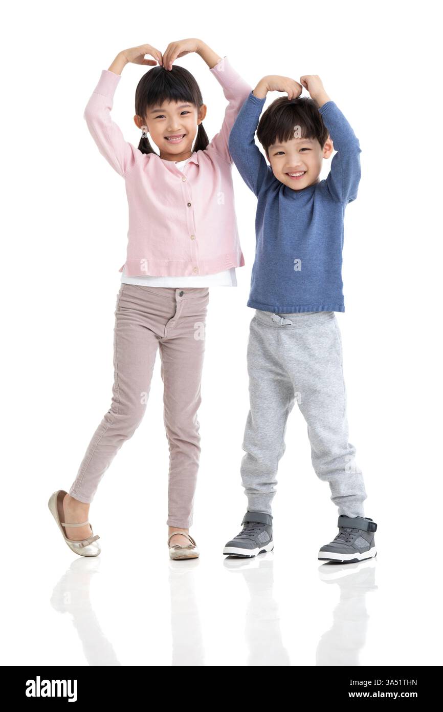 Garçon et fille chinois faisant un geste de coeur tout en se tenant debout sur fond blanc dans le studio Banque D'Images