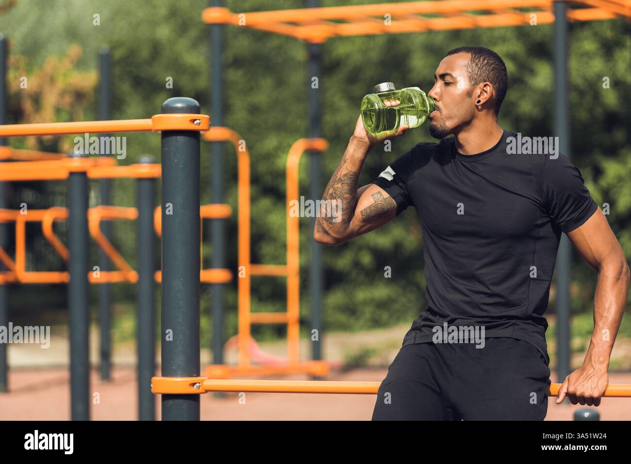 Homme africain buvant de l'eau après l'entraînement en plein air, se reposant avec de l'espace pour la copie. Ce tir de style de vie de fitness transmet de l'énergie et de la récupération, idéal pour le sport, l'hydratation et les campagnes de santé. Convient pour les gymnases, les programmes d'entraînement et les marques sportives. Banque D'Images