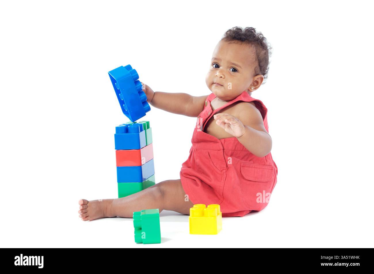 Adorable bébé fille jouant avec des blocs de construction dans un cadre de studio. Idéal pour l'éducation précoce, la créativité et l'imagerie familiale. Banque D'Images