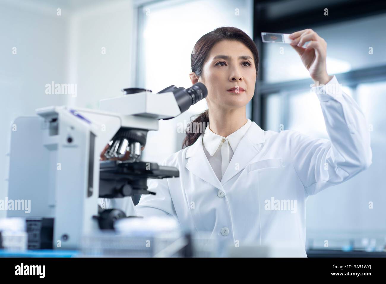 Un scientifique chinois examine une lame de microscope dans un laboratoire. Une image scientifique professionnelle adaptée à la biotechnologie, aux soins de santé et aux communications de recherche. Banque D'Images