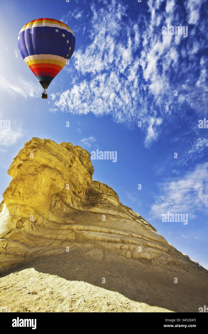 Le ballon décoratif lumineux vole au-dessus du désert de pierre sur un coucher de soleil Banque D'Images