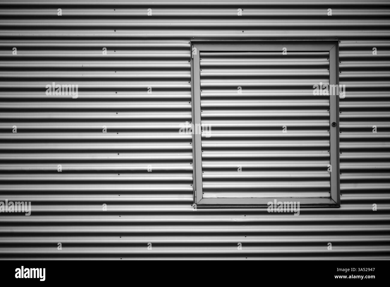 Gros plan de la façade en tôle ondulée d'un bâtiment industriel avec un cadre de fenêtre métallique Banque D'Images Gros plan de la façade en tôle ondulée d'un bâtiment industriel avec un cadre de fenêtre métallique Banque D'Images