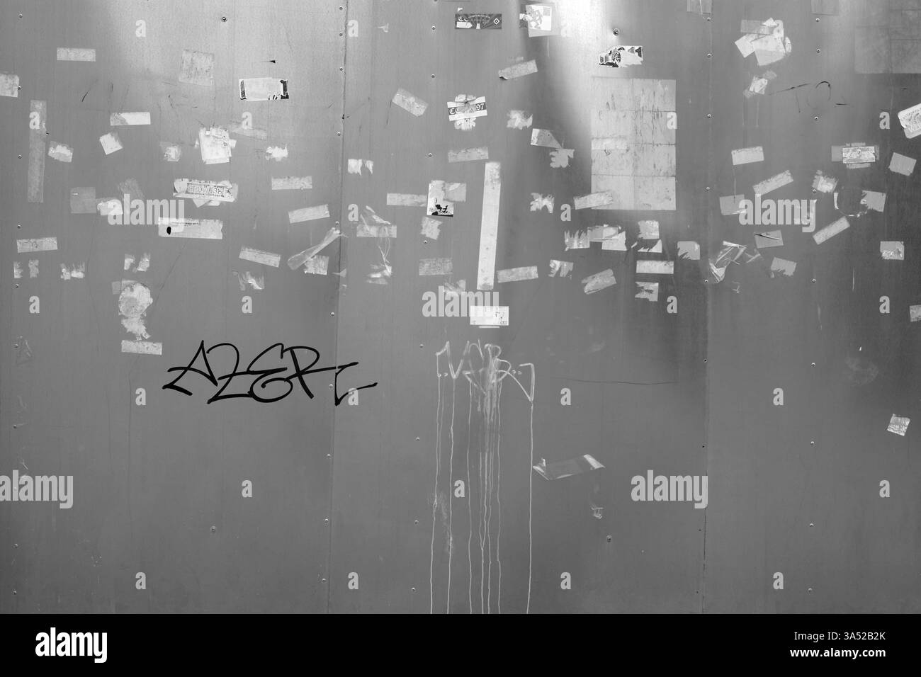 Gros plan d'un panneau d'affichage métallique avec des morceaux de papier arrachés d'affiches et d'autocollants Banque D'Images