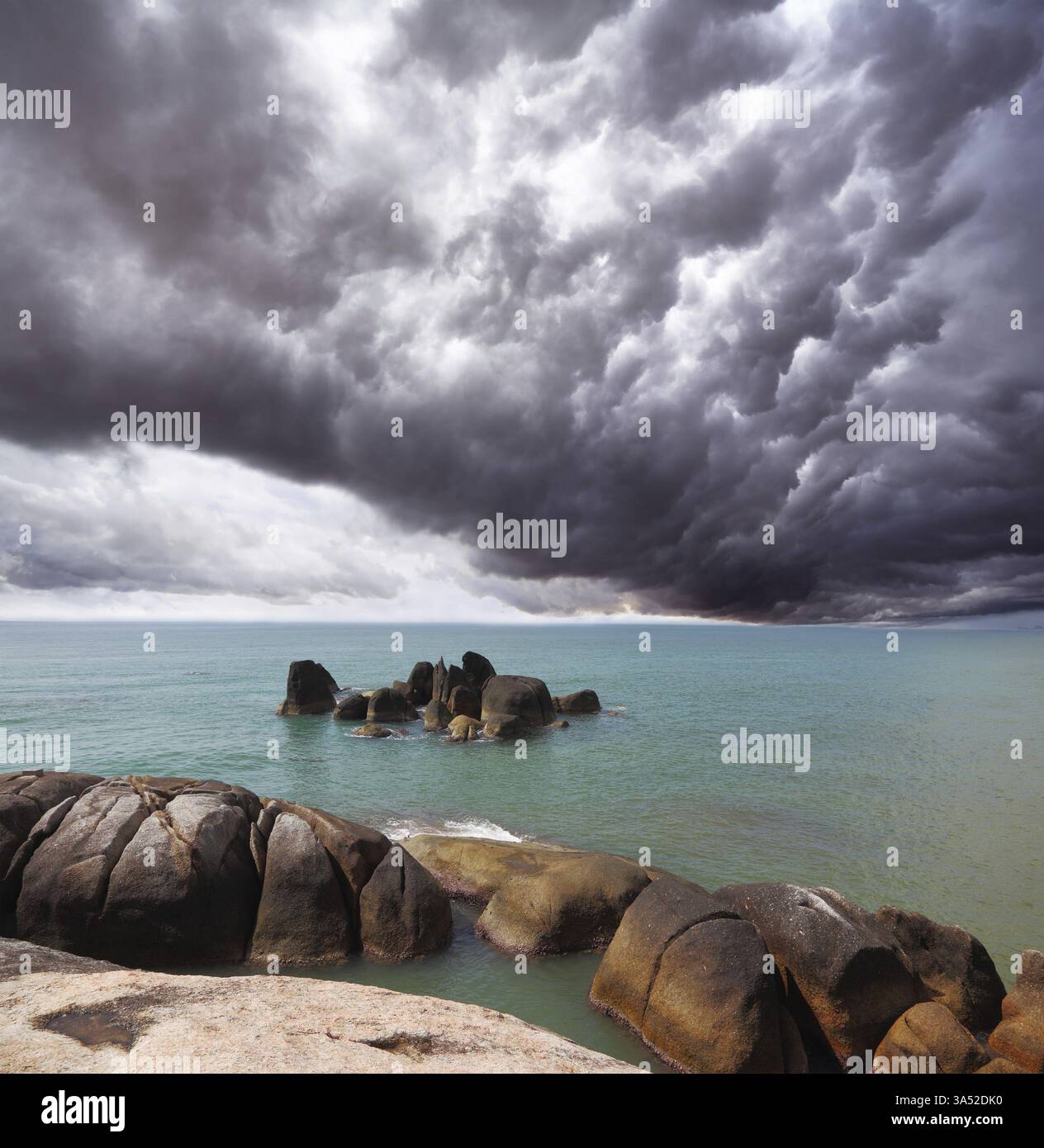 Nuage de tempête au-dessus de la mer du sud. Les rochers côtiers brillent sous le soleil du coucher du soleil Banque D'Images