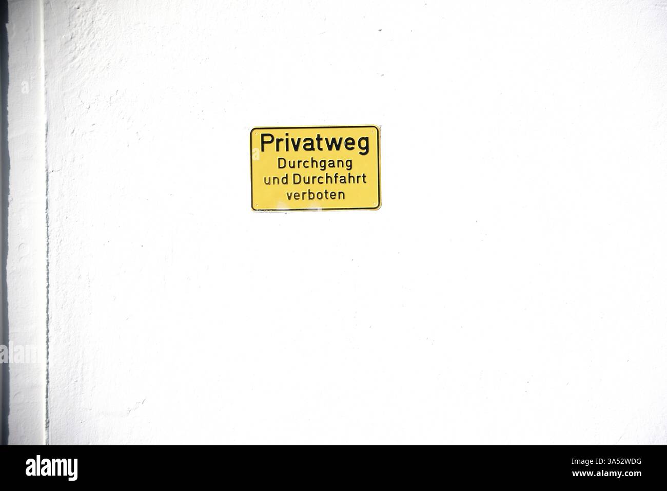 Un panneau jaune sur un mur de maison de couleur claire avec l'inscription : chemin privé, passage et passage interdit Banque D'Images