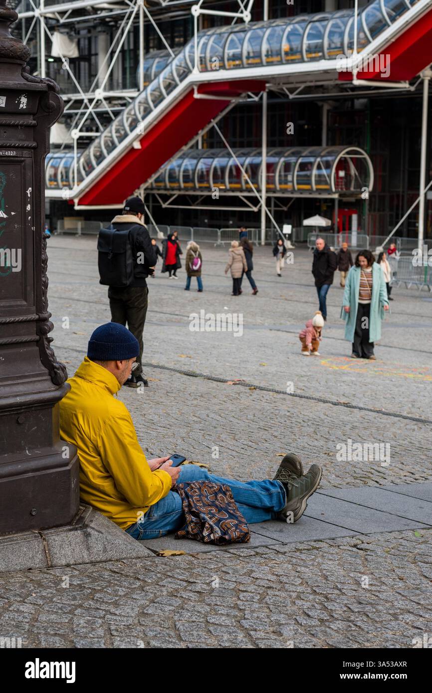 Un homme est assis sur le parvis du Centre Pompidou à Paris, France. La Piazza fait partie intégrante du complexe culturel. Banque D'Images