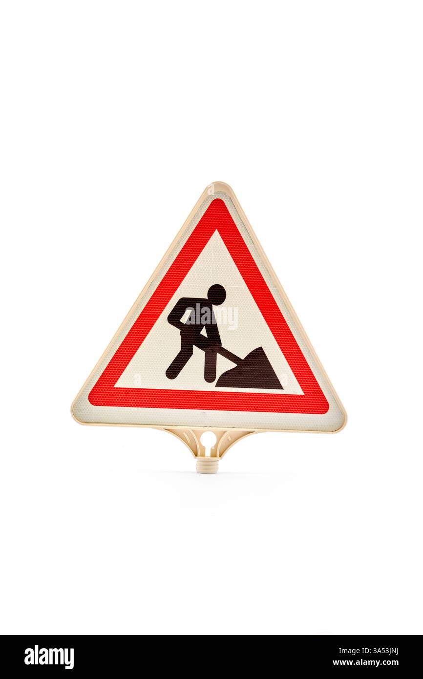 Avertissement panneau de construction de forme triangulaire avec bordure rouge et icône noire d'un travailleur avec une pelle représentant les travaux routiers à venir, essentiels pour Banque D'Images
