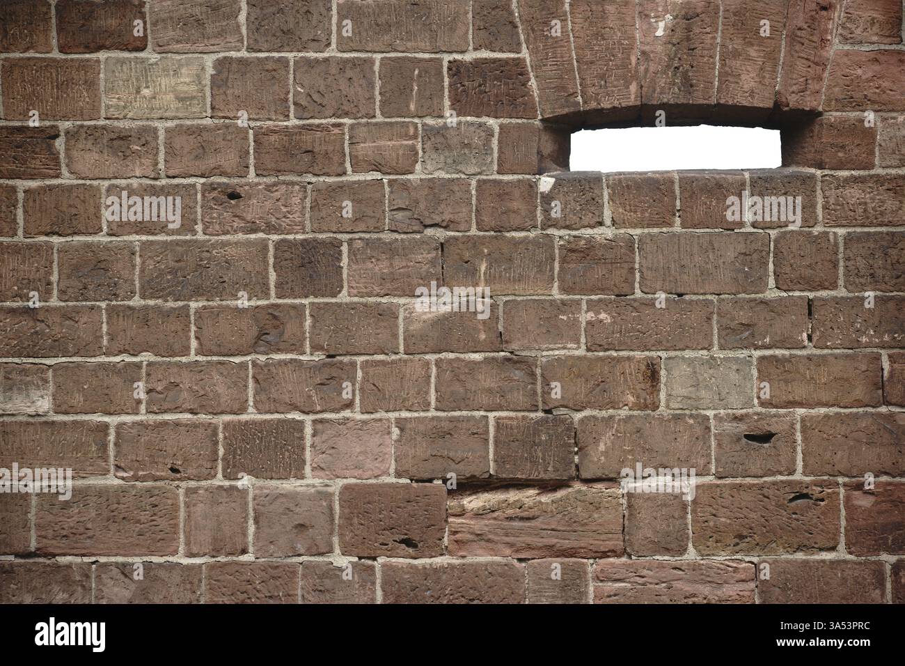 Un mur de pierres rouge vin frappantes avec une embrasure ou une fenêtre Banque D'Images