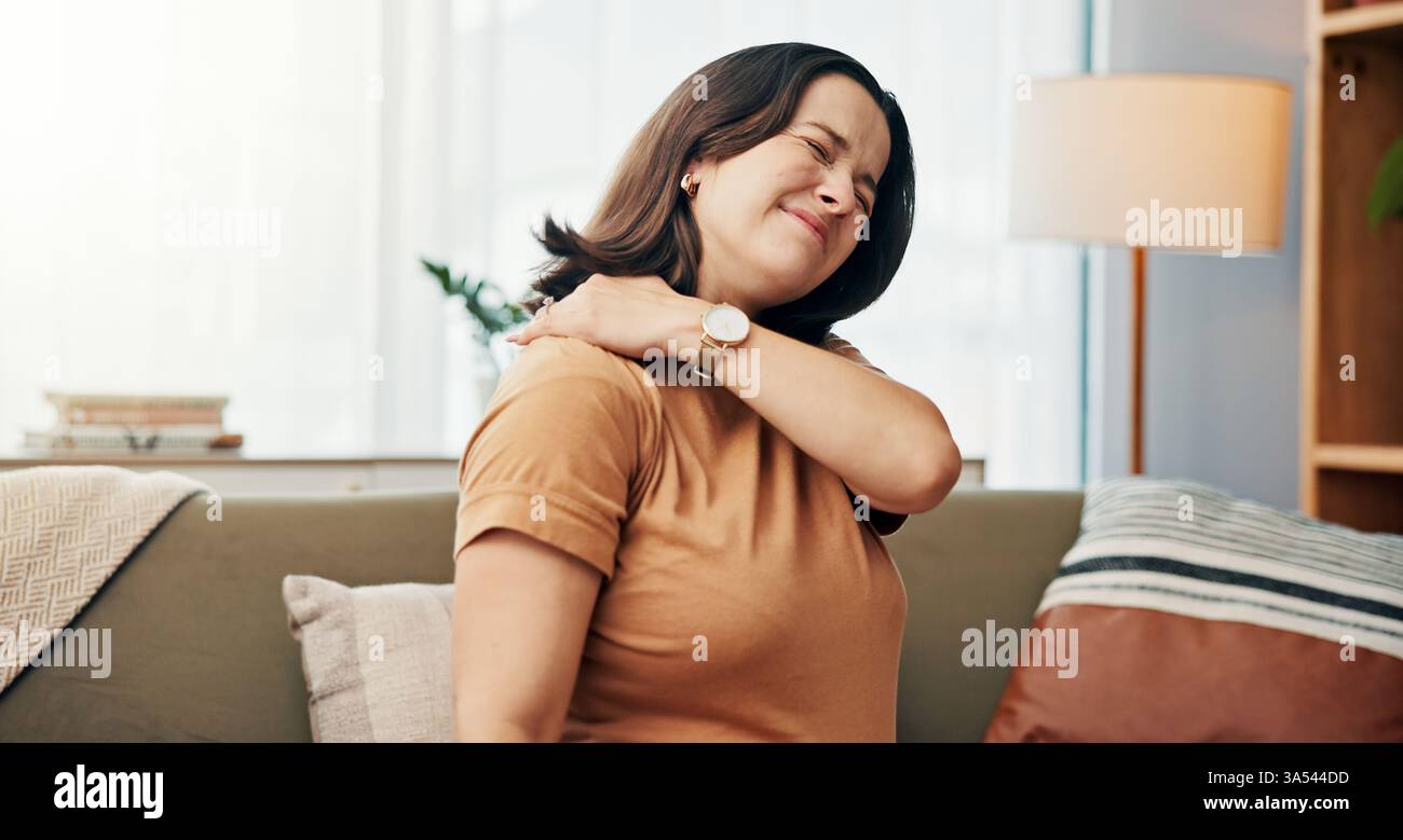 Douleur à l'épaule, massage et femme sur canapé à la maison avec stress, tension musculaire et blessure dans le salon. Santé, burnout et personne fatiguée avec médical Banque D'Images