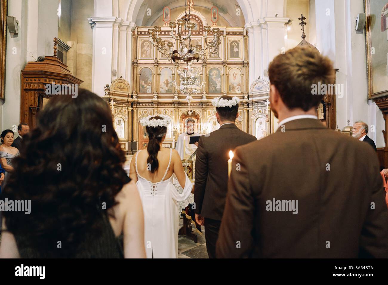 Monténégro, Kotor - 13 juillet 2024 : les invités se tiennent dans l'église derrière les mariés dans des couronnes devant le prêtre pendant la cérémonie de mariage Banque D'Images