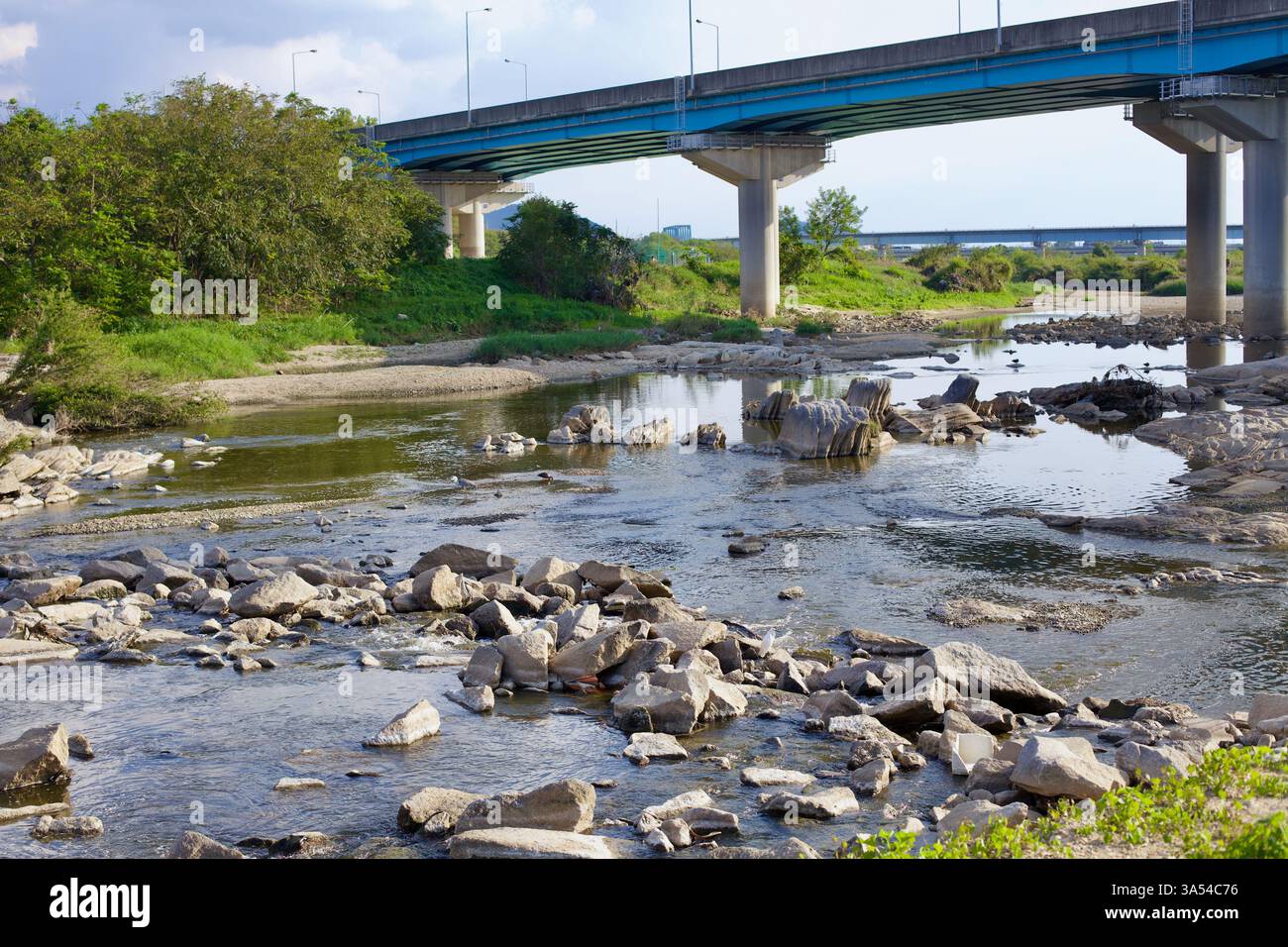 Gwangju, Corée du Sud - 24 septembre 2020 : un lit de rivière rocheux avec des rochers dispersés coule sous un pont de béton le long du Yeongsangang, entouré Banque D'Images