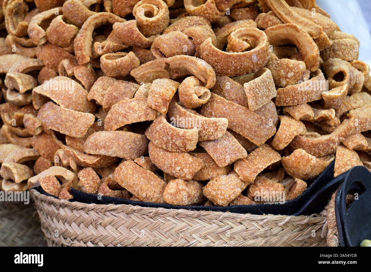 Gros plan d'un monticule de ventre de porc frit croustillant empilé dans un panier en osier. La texture dorée et croquante met en valeur la préparation salée de cette classe Banque D'Images