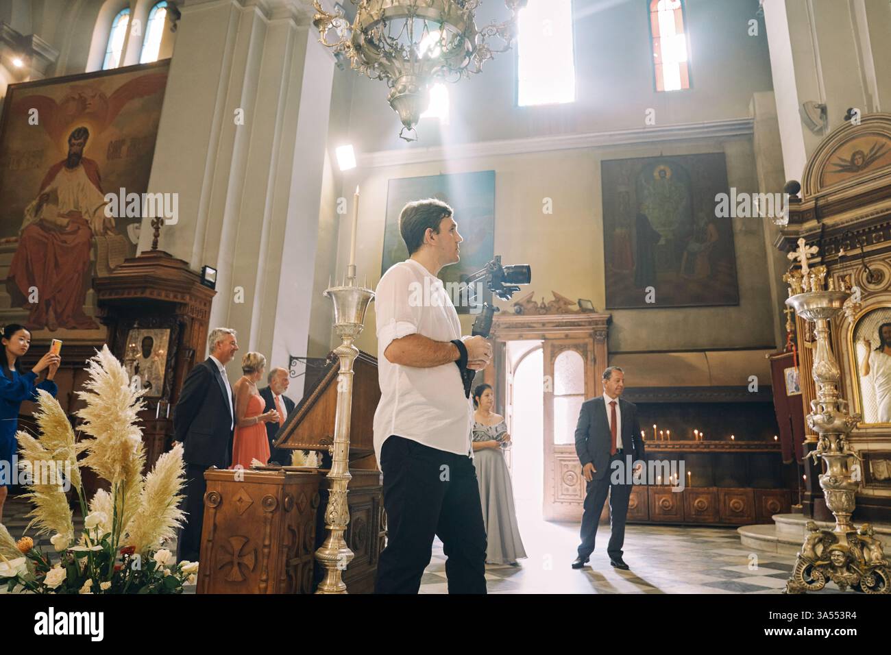 Monténégro, Kotor - 13 juillet 2024 : le photographe filme une cérémonie de mariage dans une église avec un appareil photo sur un trépied. Vue latérale Banque D'Images
