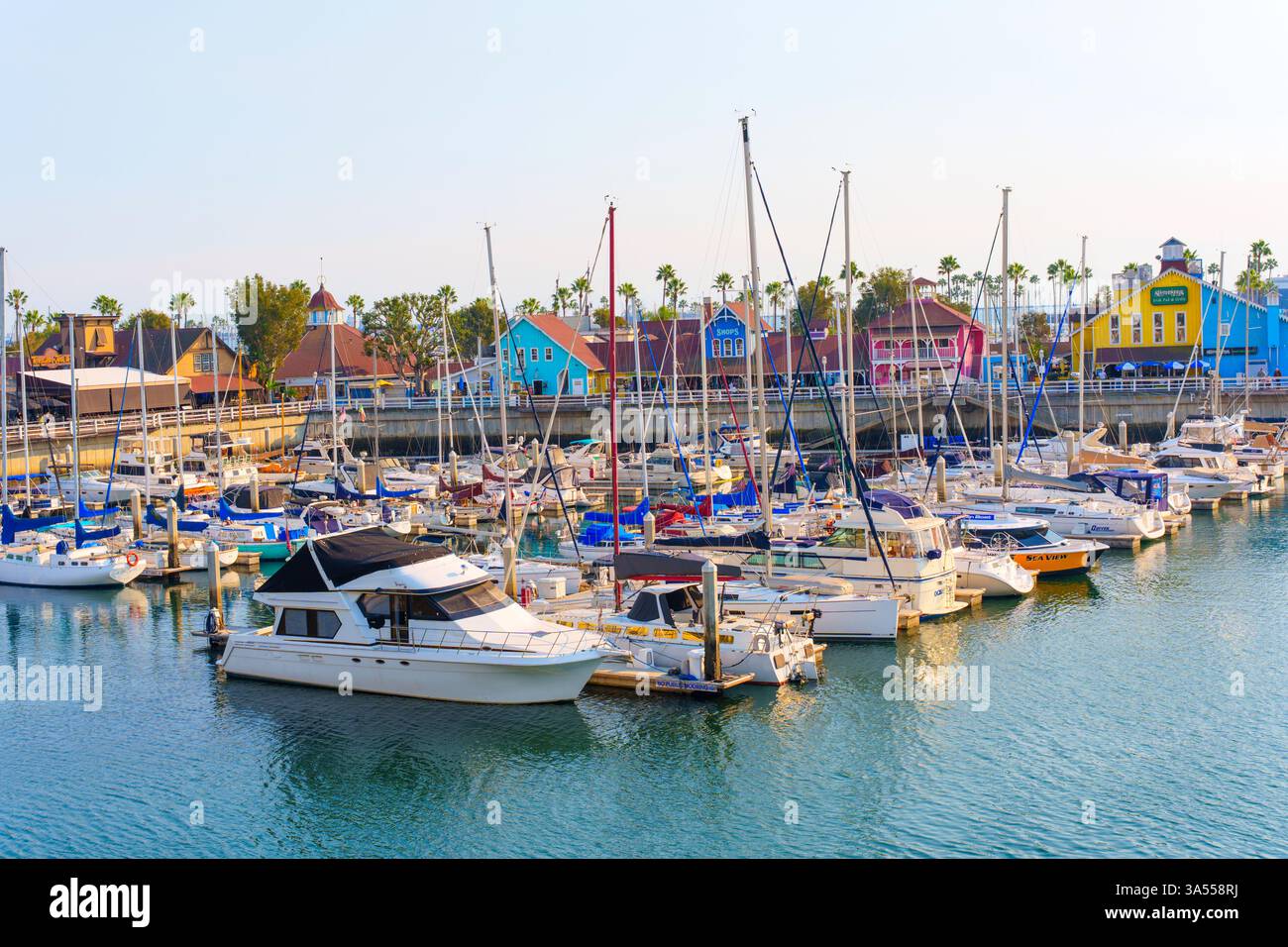 Long Beach, Californie - 11 janvier 2025 : bateaux colorés amarrés dans les eaux calmes de Rainbow Harbor, entourés par les bâtiments animés du rivage Banque D'Images