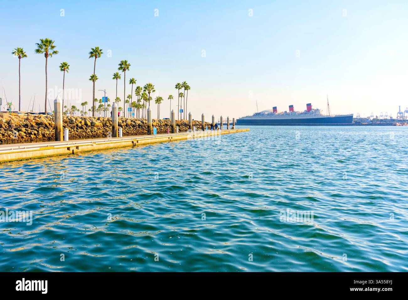 Long Beach, Californie - 11 janvier 2025 : vue imprenable sur le navire historique Queen Mary depuis les eaux sereines de long Beach, encadrées par des palmiers et Banque D'Images
