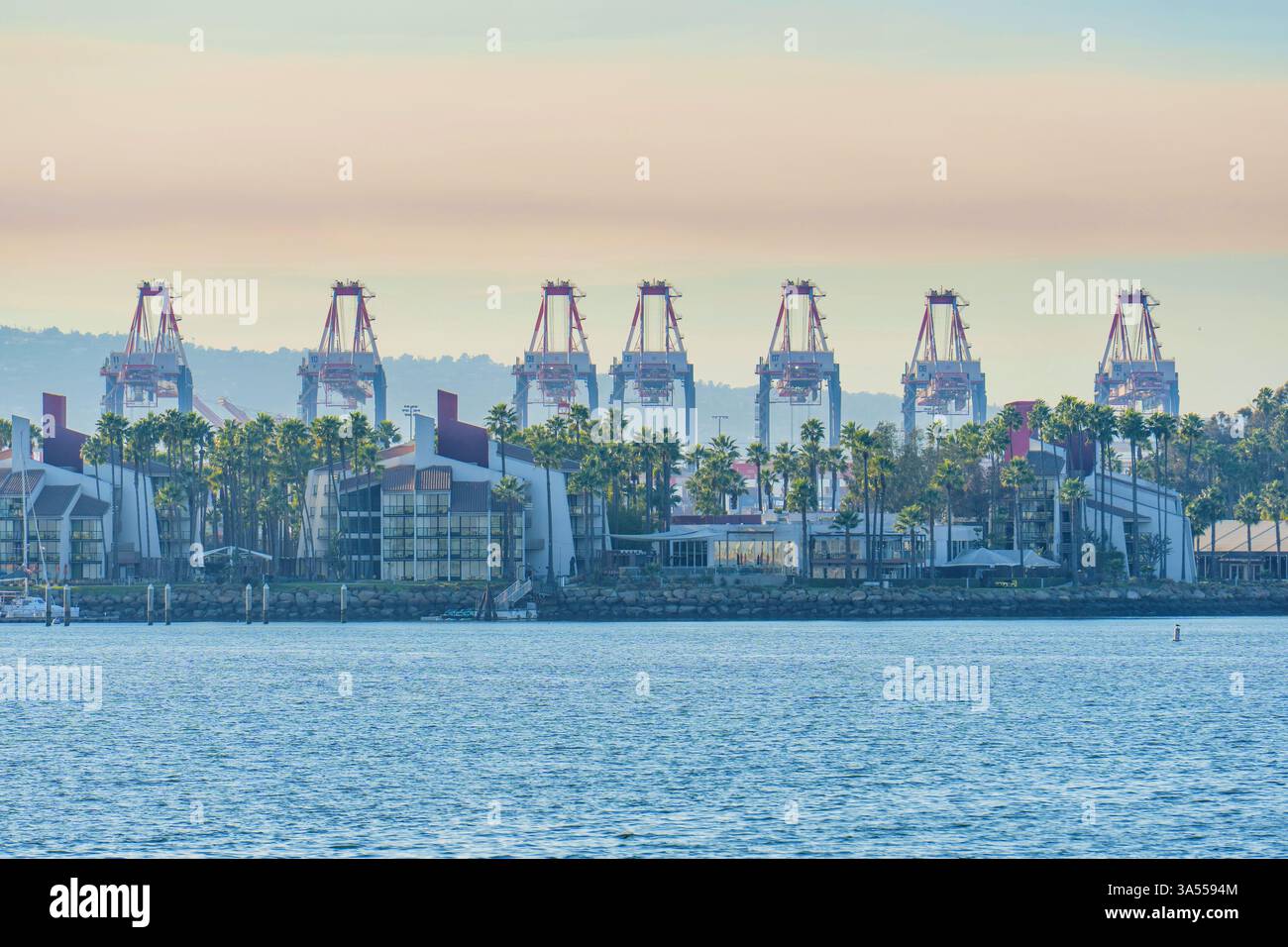Long Beach, Californie - 11 janvier 2025 : vue sur les luxueux immeubles d'appartements modernes au bord de l'eau dans le port de long Beach, avec les grues portuaires imposantes i. Banque D'Images