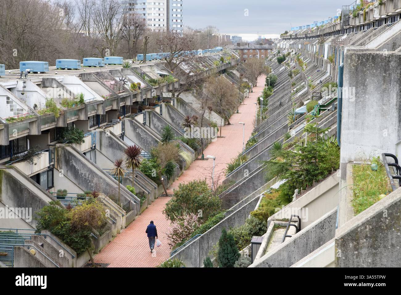 Une seule personne marchant dans le style brutaliste Alexandra et Ainsworth Estate le long de Rowley Way dans le quartier londonien de Camden Banque D'Images