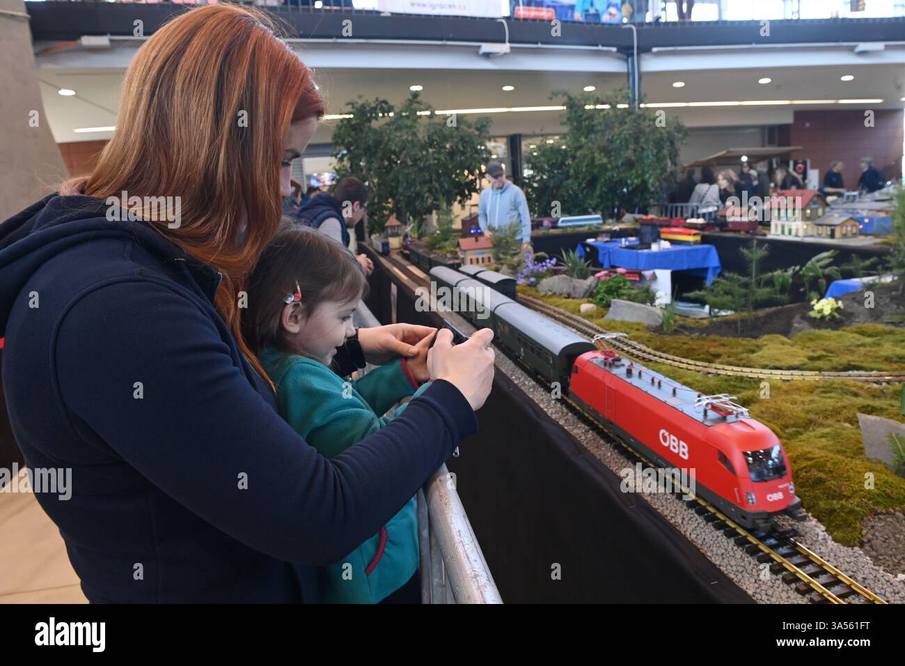 Olomouc, République tchèque. 21 mars 2025. Les modélisateurs aéronautiques, navals et automobiles ont préparé leurs expositions à la veille de la 23ème édition de l'exposition interactive for Model 2025, axée sur les modèles, la collecte et les technologies numériques, les jeux, les jouets et les kits, Olomouc, République tchèque, 21 mars 2025. Une femme avec un enfant prend une photo du chemin de fer de jardin modèle de Jan Bartos. Crédit : Ludek Perina/CTK photo/Alamy Live News Banque D'Images