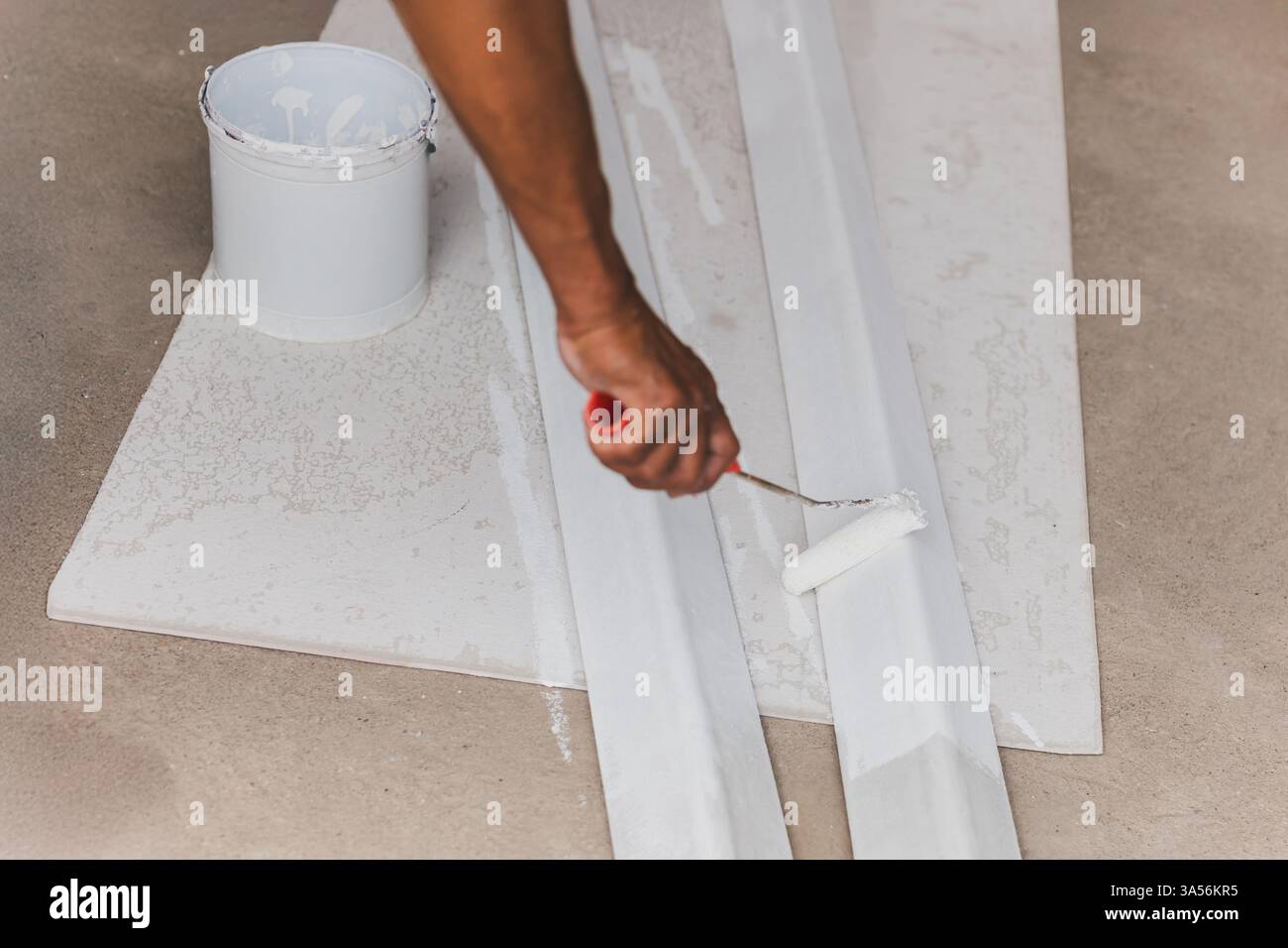 Peindre une boîte en métal pour un nouveau toit avec un peintre à rouleaux. Banque D'Images