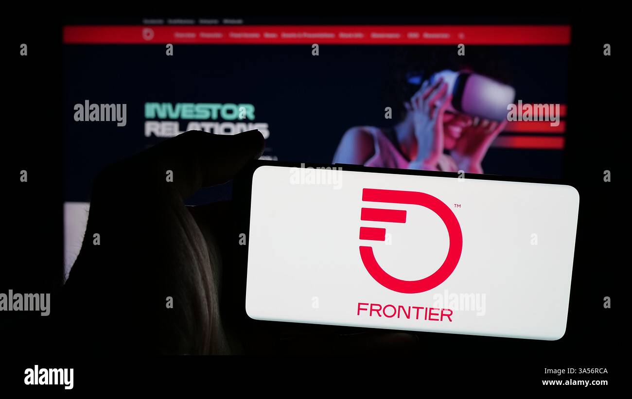 Stuttgart, Allemagne - 11-13-2024 : personne tenant un téléphone portable avec le logo de la société américaine Frontier Communications parent Inc sur l'écran Banque D'Images