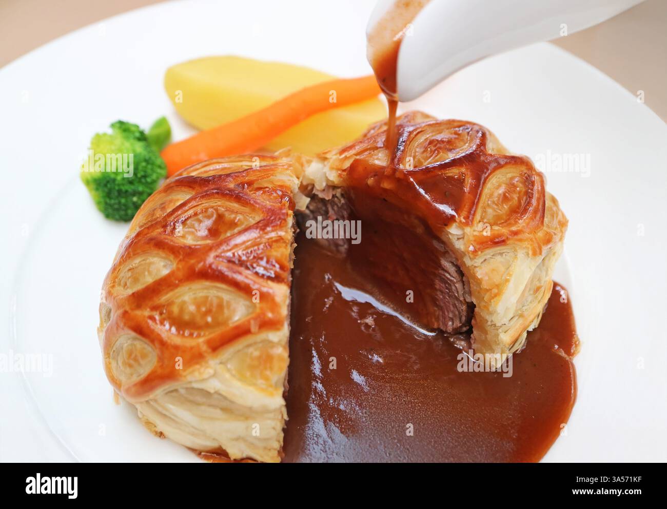Gros plan sur l'appétissant Wellington de bœuf versé avec une sauce au vin rouge Banque D'Images