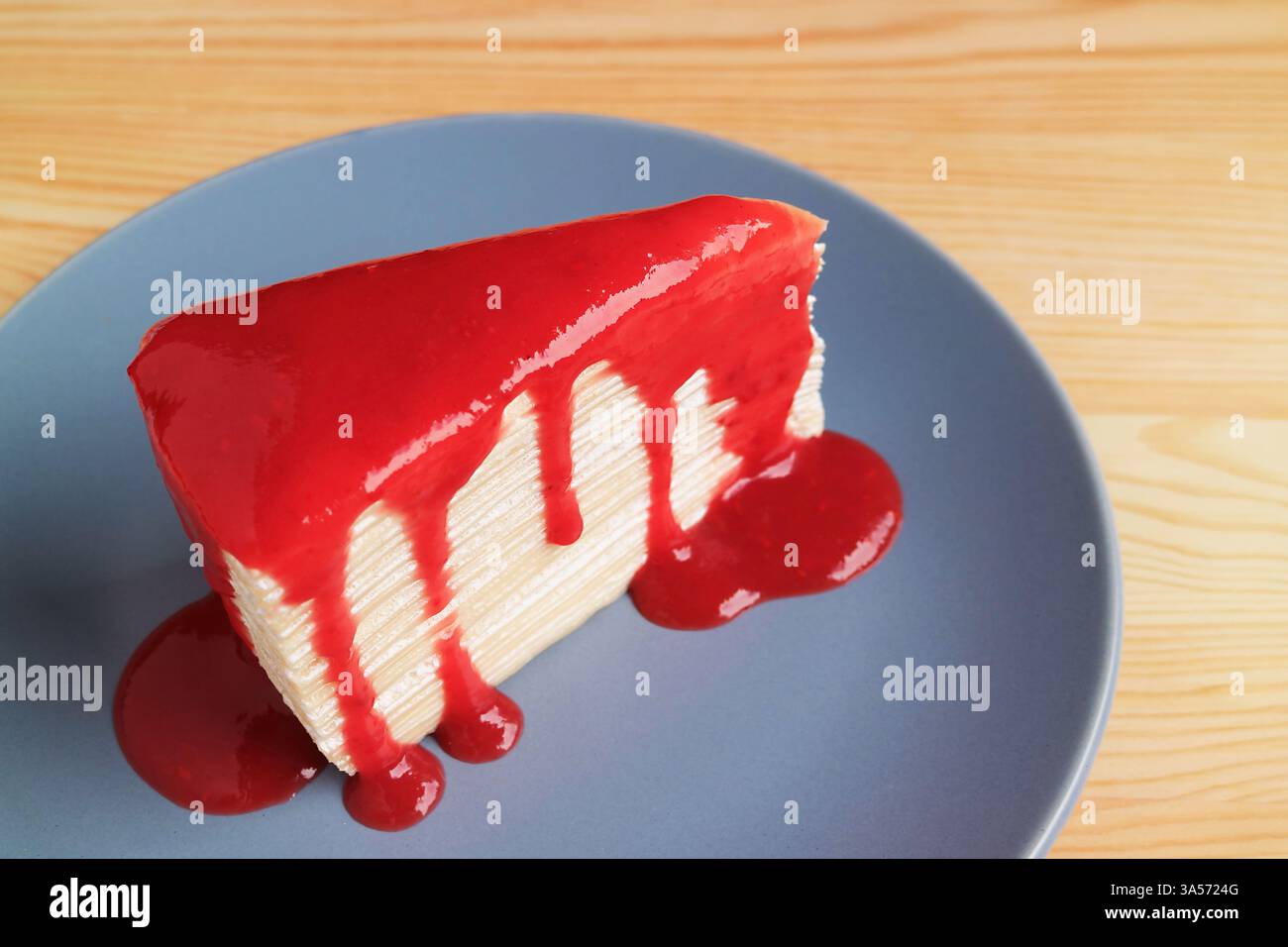 Tranche de délicieux gâteau à la vanille mille crêpe avec sauce framboise rouge vif Banque D'Images