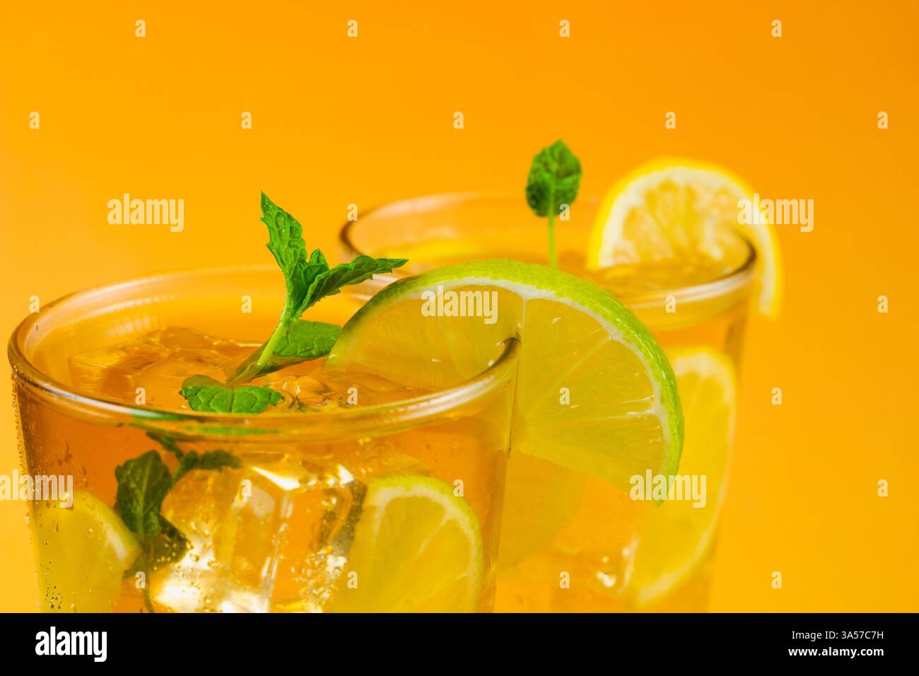 Gros plan de deux verres de thé glacé avec des tranches de citron vert et de citron. La boisson est servie dans un verre avec des feuilles de menthe sur le dessus. Banque D'Images
