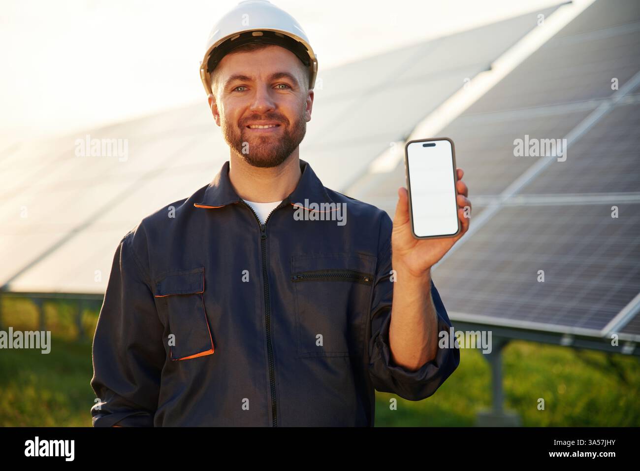 Smartphone avec espace de copie. L'homme travaille avec des panneaux solaires à l'extérieur pendant la journée. Banque D'Images
