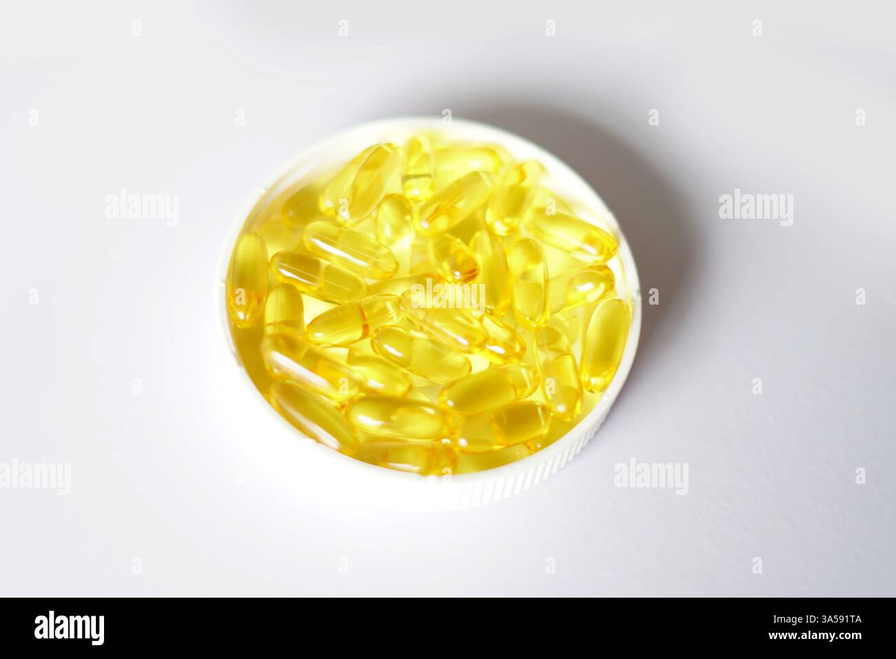 capsules d'huile de foie de morue, capsules de poisson, capsules d'huile de foie de morue dans le couvercle de bouteille. fond blanc Banque D'Images