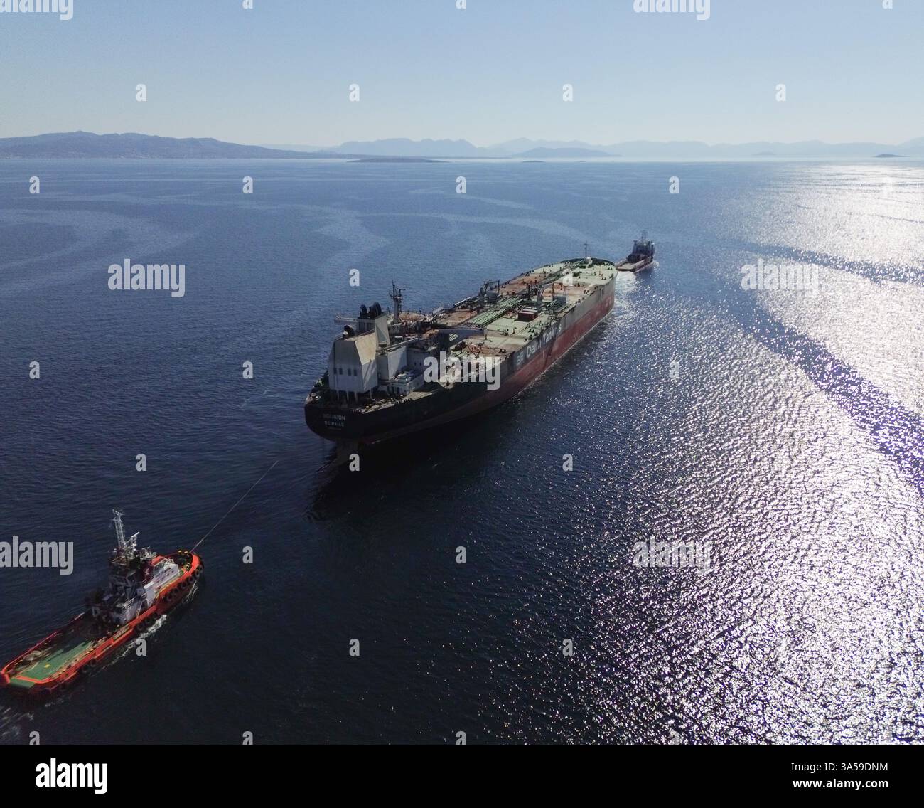 Pirée, Grèce. 21 mars 2025. Dans une vue aérienne, le pétrolier grec Sounion, gravement endommagé, est remorqué par deux petits navires au mouillage du Pirée. Le pétrolier Sounion, endommagé par les Houthis lors de multiples attaques au large du Yémen en août 2024, est arrivé en Grèce. Crédit : Dimitris Aspiotis/Alamy Live News Banque D'Images