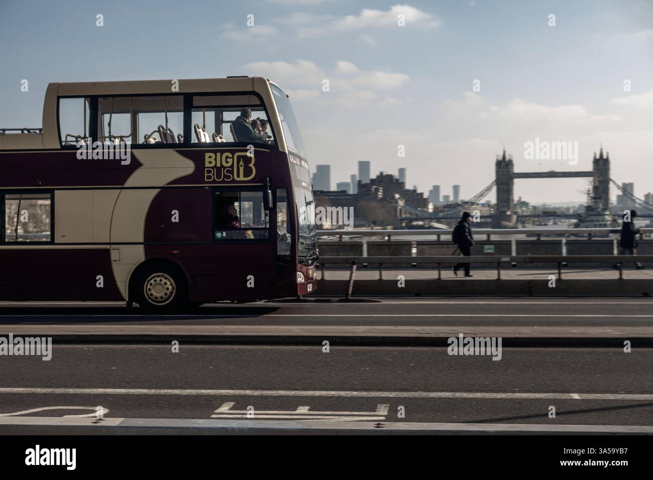 Londres, 14 février 2025 : un Big bus Hop on - Hop Off à deux étages sur London Bridge, Tower Bridge en arrière-plan. Banque D'Images