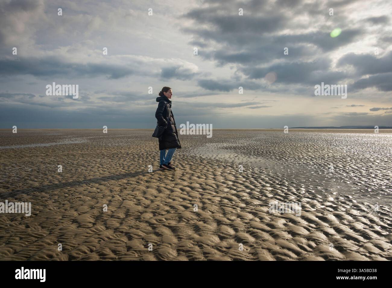 femme debout sur la plage vide à marée basse, Banque D'Images femme debout sur la plage vide à marée basse, Banque D'Images