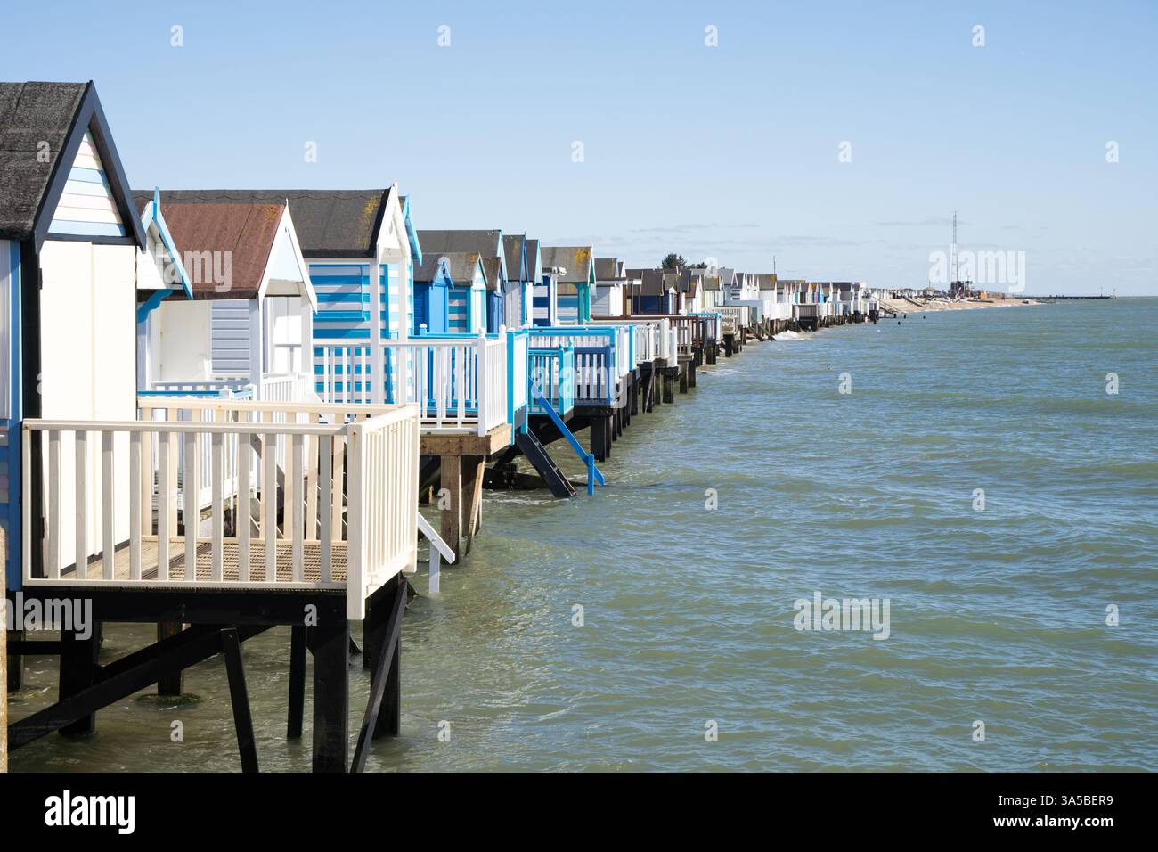 Rangée de cabanes de plage qui brille au soleil au-dessus de l'eau de mer dans Southe-on-Sea Essex Angleterre Royaume-Uni Banque D'Images