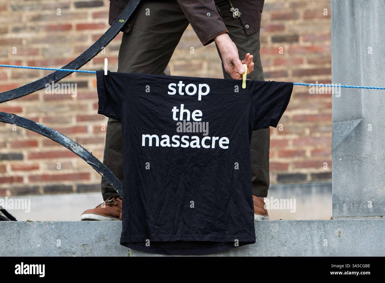 Bristol, Royaume-Uni. 22 mars 2025. Un partisan pro-palestinien est photographié accrochant des T-shirts « arrêtez le massacre » sur les rampes devant l'hôtel de ville de Bristol avant une marche de protestation pro-palestinienne dans le centre-ville de Bristol. La marche de protestation et le rassemblement d'urgence 'End the Genocide, Ceasefire Now !' ont été organisés par divers groupes de soutien palestiniens de Bristol, la coalition Bristol STOP the War et le Bristol Trades union council. Crédit : Lynchpics/Alamy Live News Banque D'Images