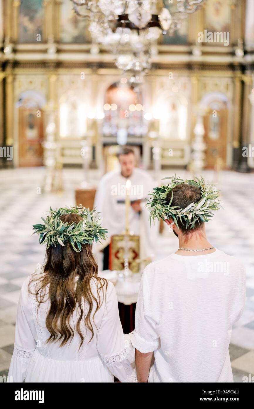 Monténégro, Kotor - 07 juillet 2024 : mariés et mariés en couronnes se tiennent devant le prêtre menant la cérémonie de mariage. Vue arrière Banque D'Images