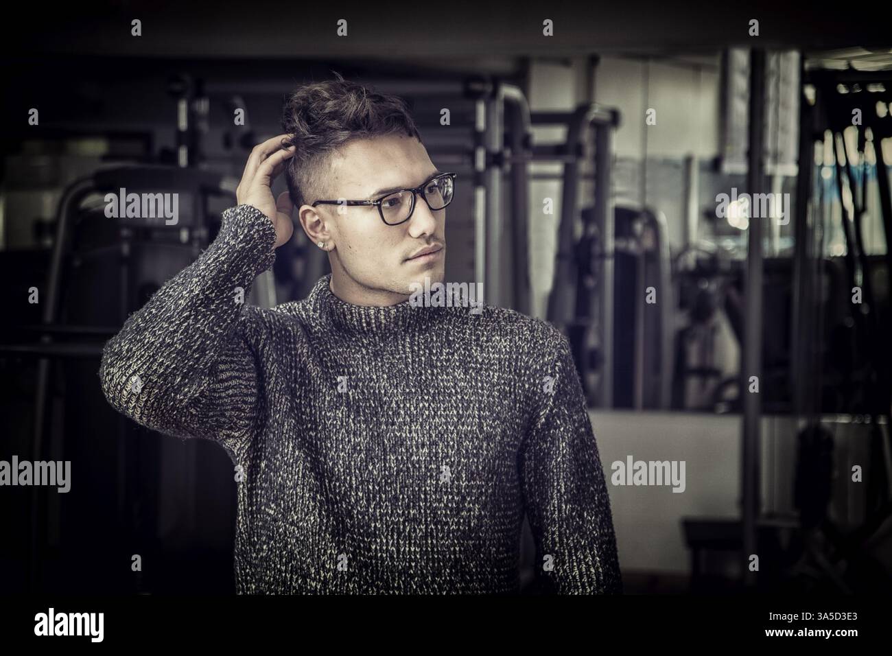 Beau jeune homme asiatique blanche portant chandail gris, debout dans l'obscurité Banque D'Images