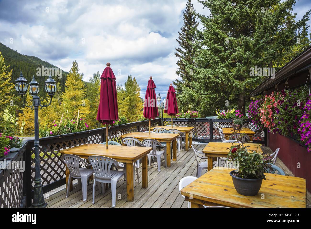 Café extérieur confortable. Vacances en automne Canada. Tables en bois, chaises en plastique et auvents rouges roulés Banque D'Images